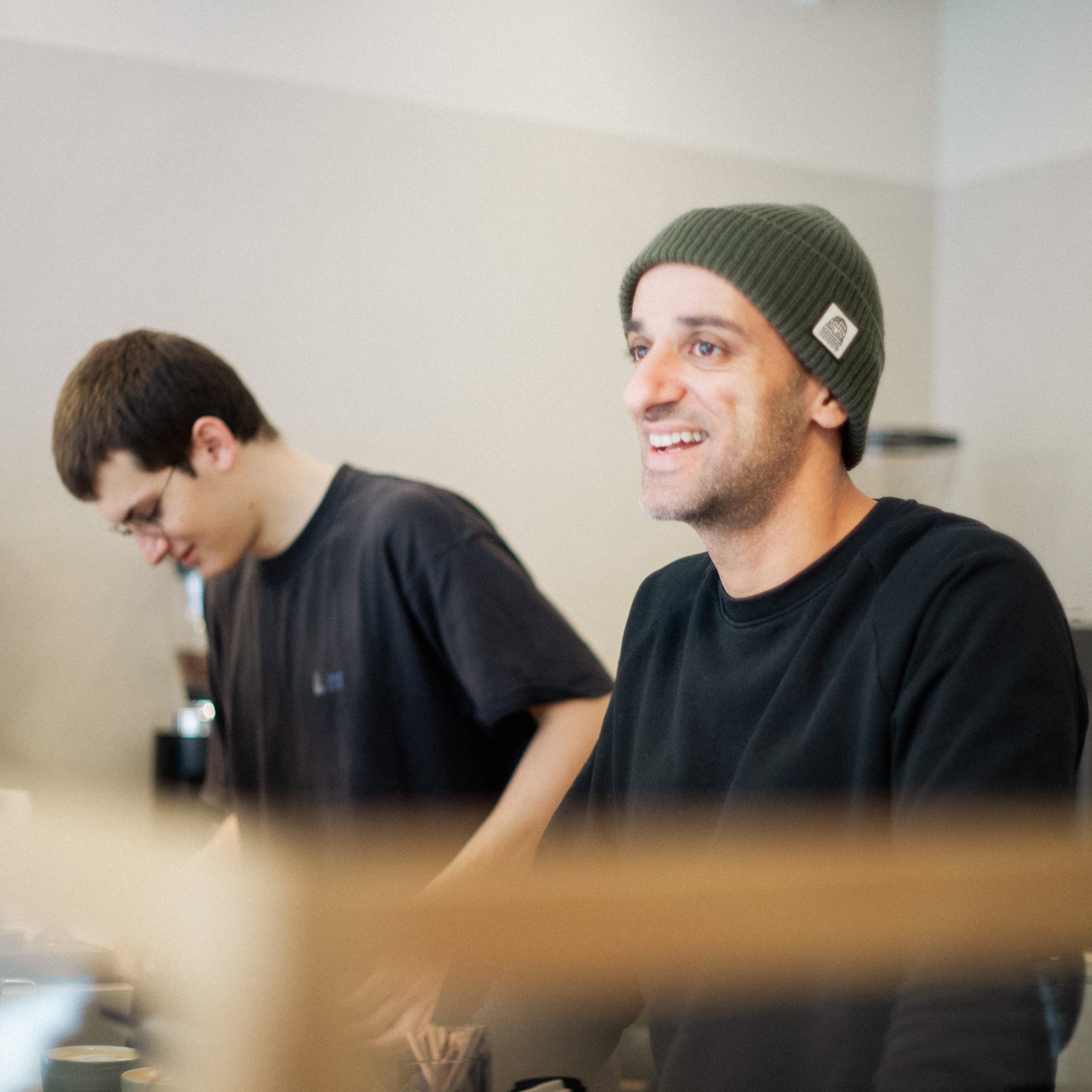 Armin Zandieh standing behind the bar smiling next to Jannik Ernst making Coffee.