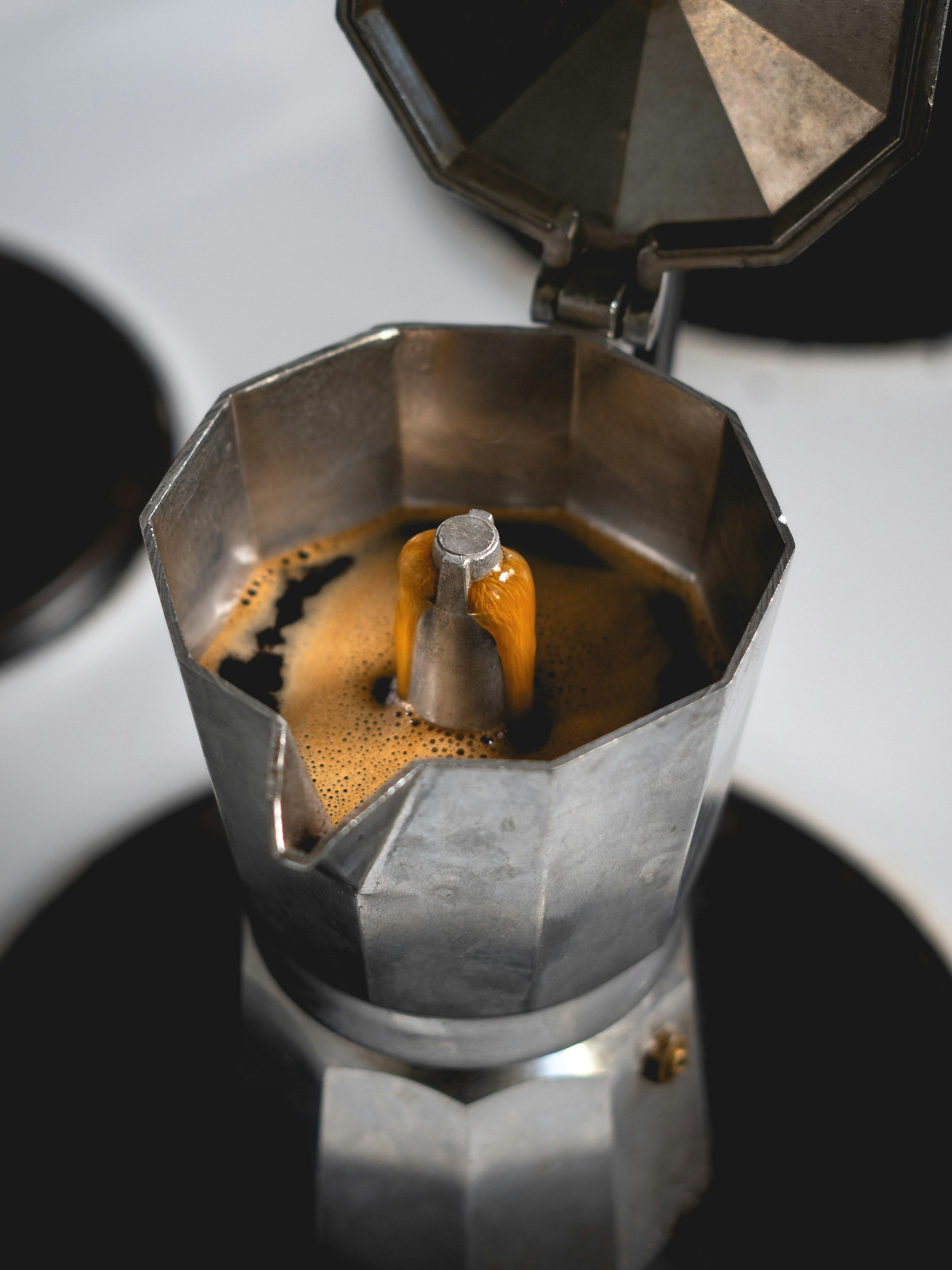 Close up of the a bialetti jug on a traditional electrical stove, with coffee currently extracting.