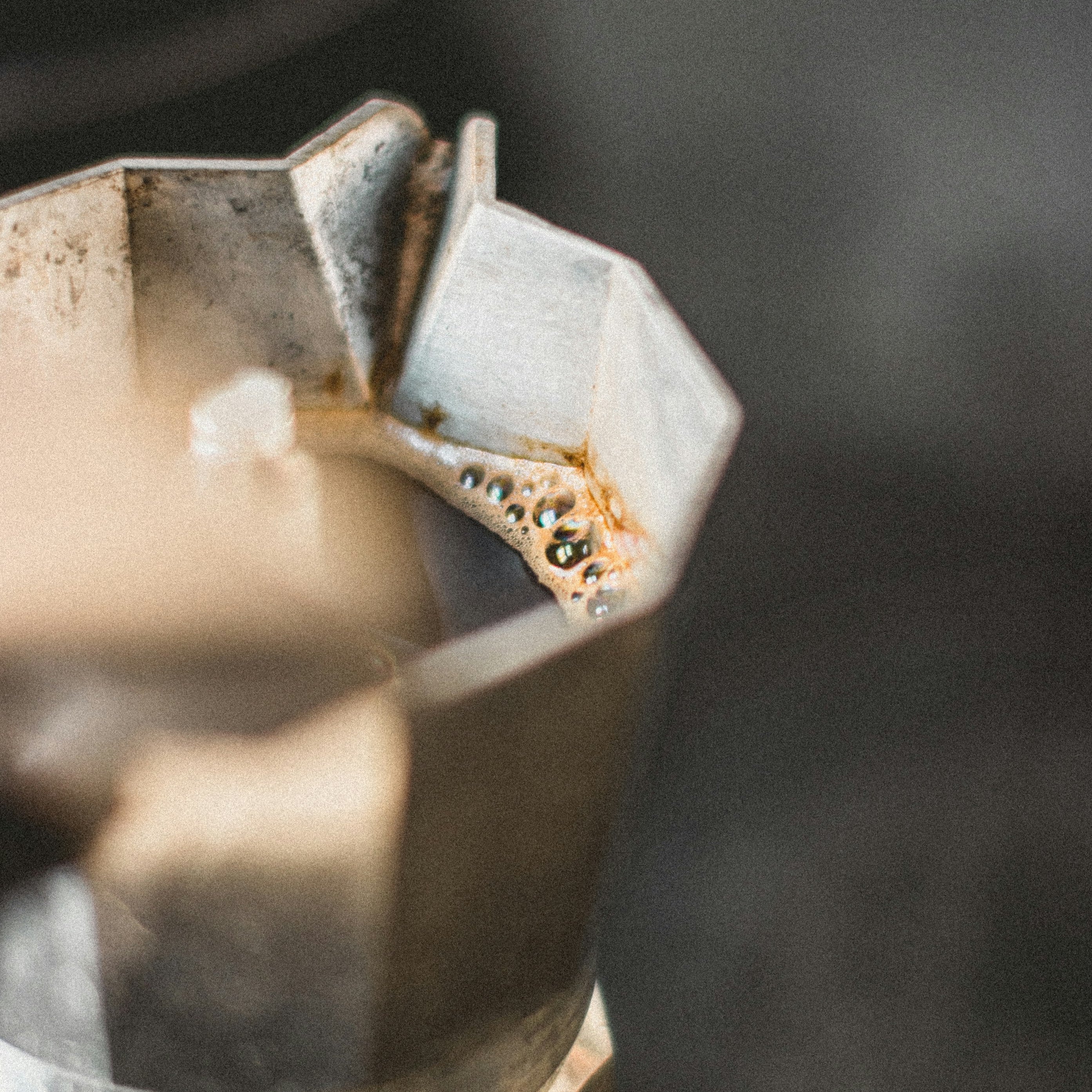 A close-up of a bialetti moka pot with open lid so that the coffee is visible.