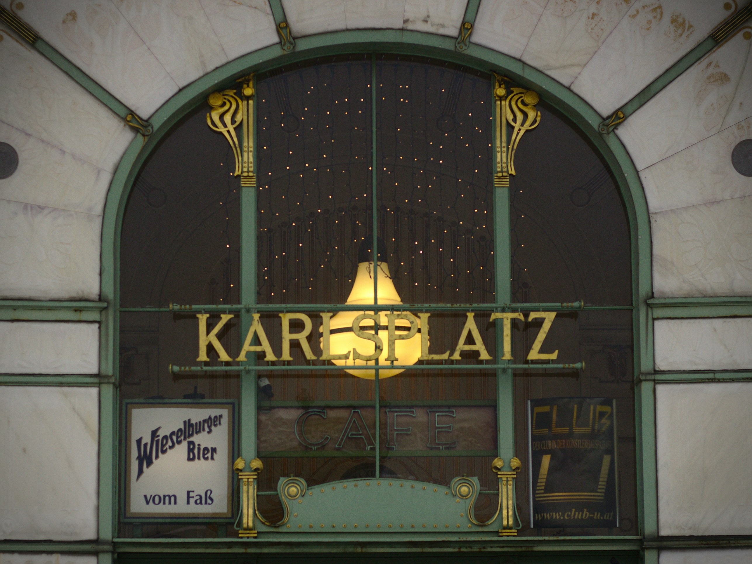 The window above the main entrance of the viennese coffeehouse on Karlsplatz with a prominent green frame and golden decorative details