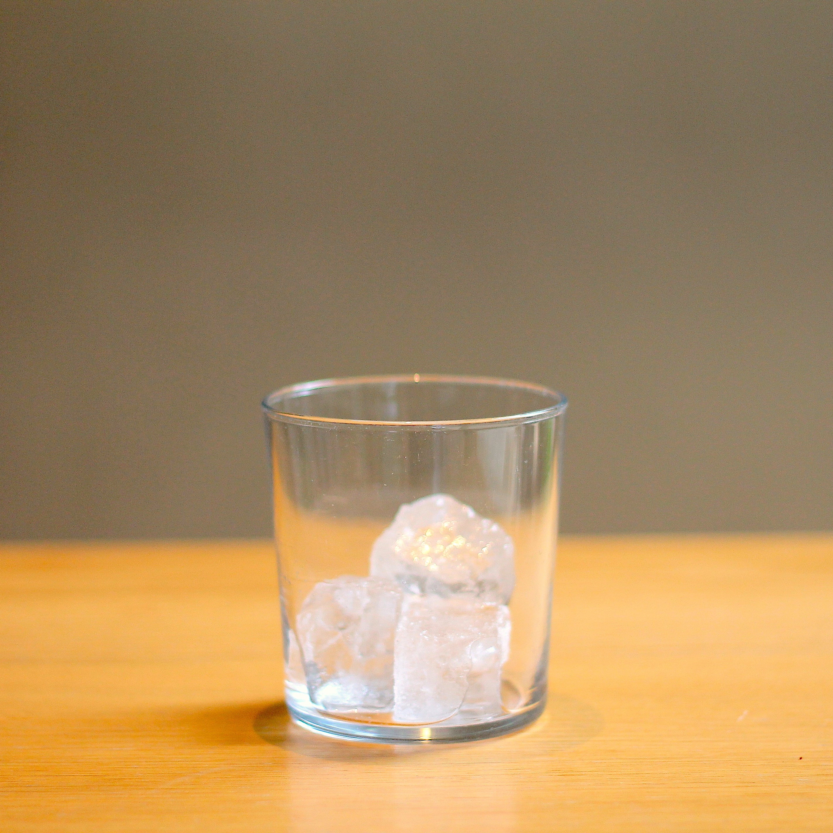 A simple round glass filled with a couple of ice cubes.