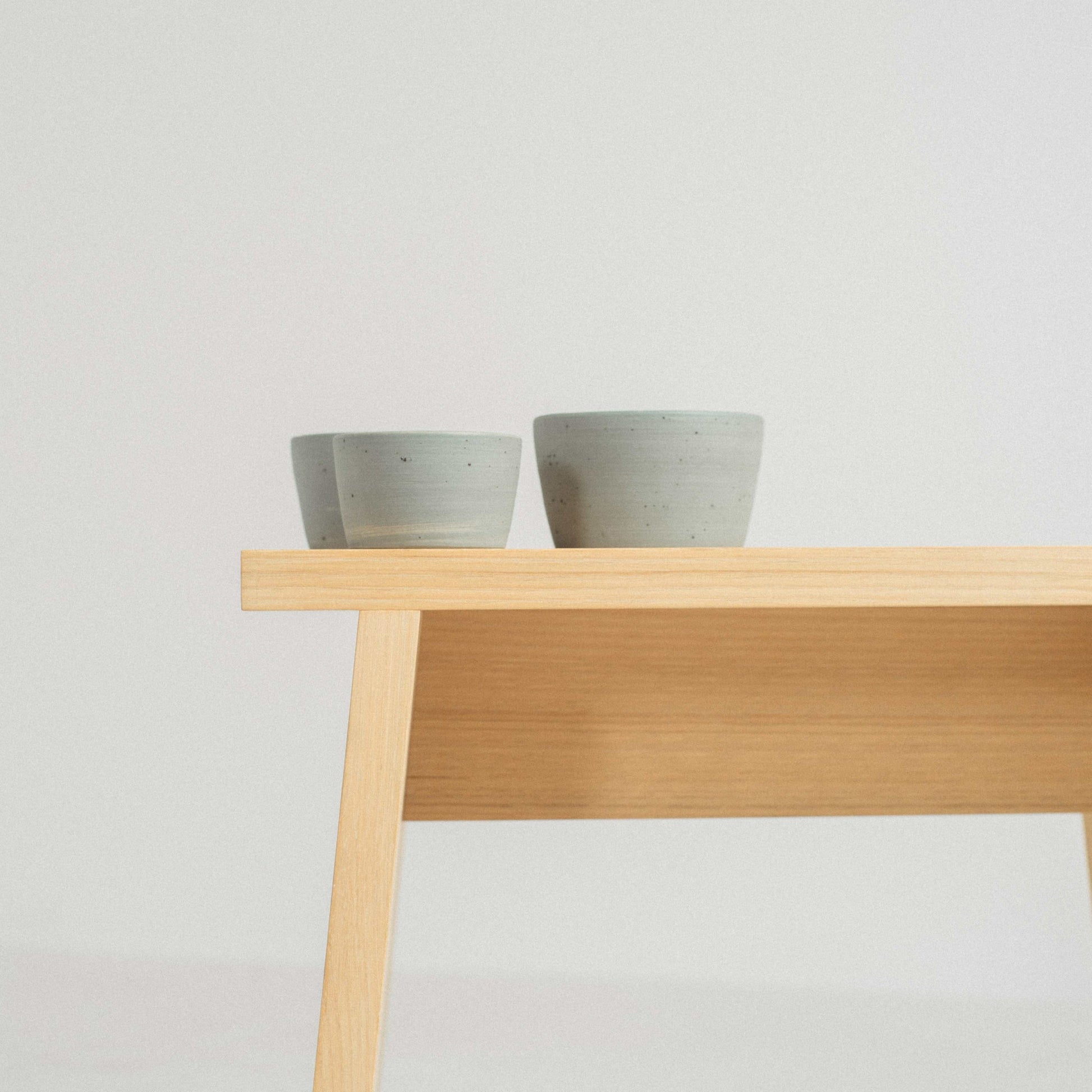 all three sizes of the iaro specialty coffee mugs photographed on a wooden stool in a profile view