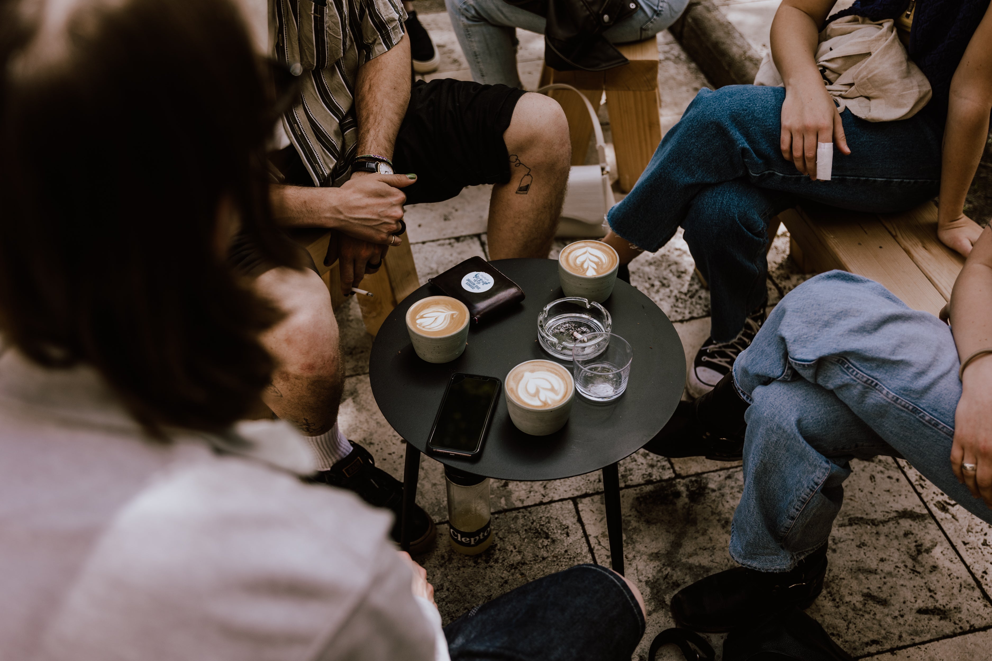 A group of young people sitting at a table with cappuccinos with beautiful latte art