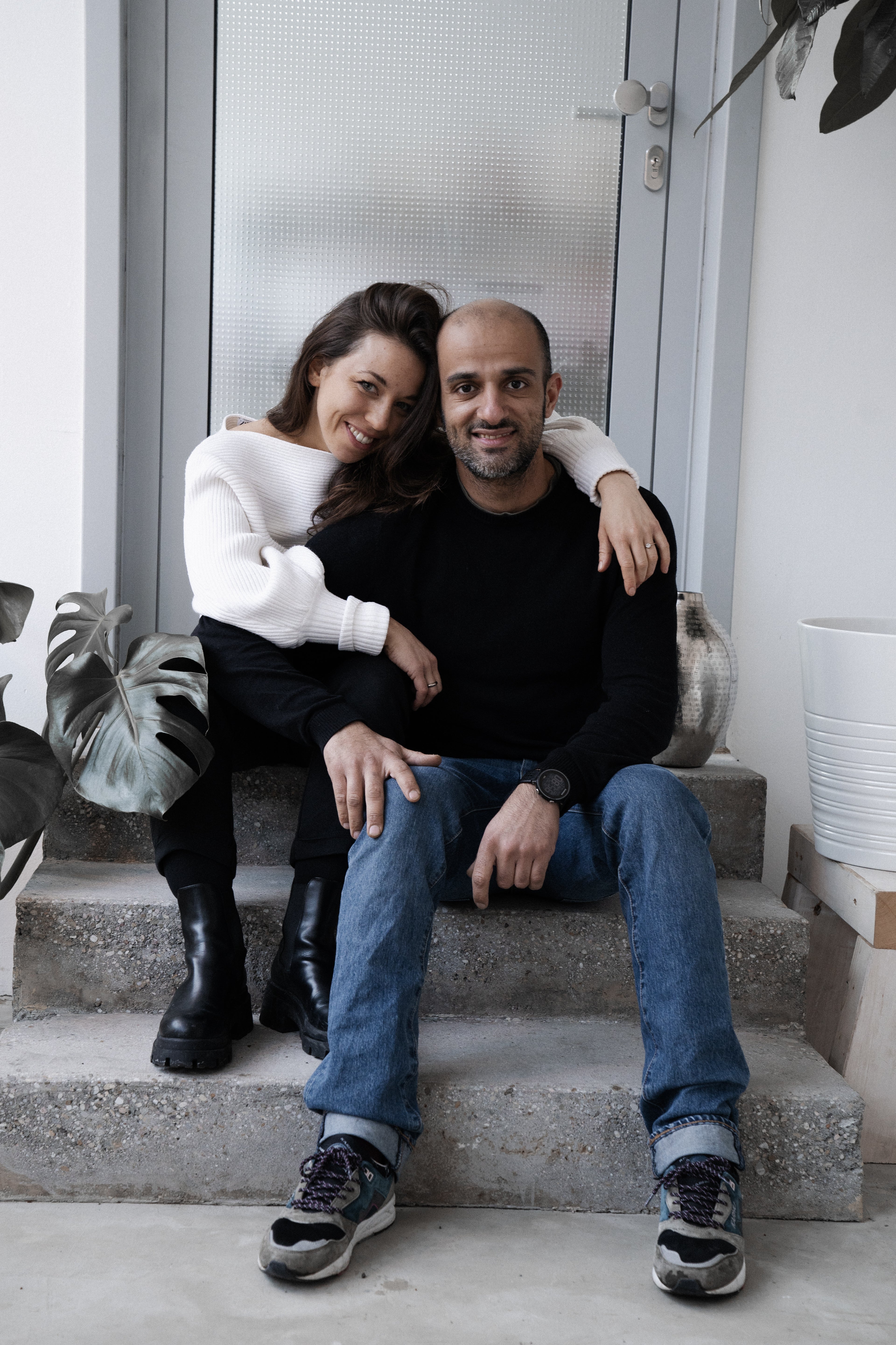 The founders of iaro Armin and Nabila sitting on a concrete stair together and smiling.