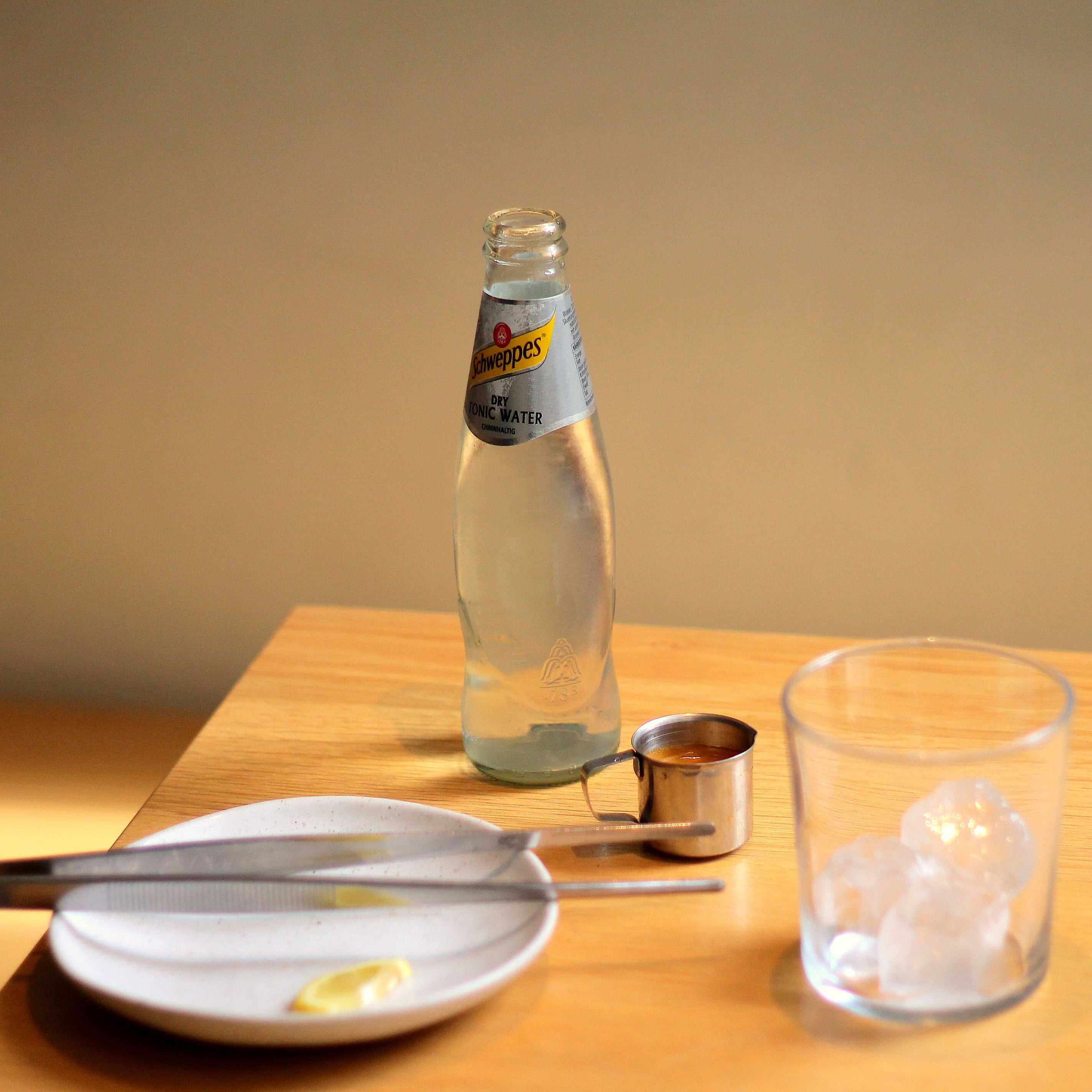 The ingredients needed to prepare an espresso tonic are presented on a wooden tabletop.