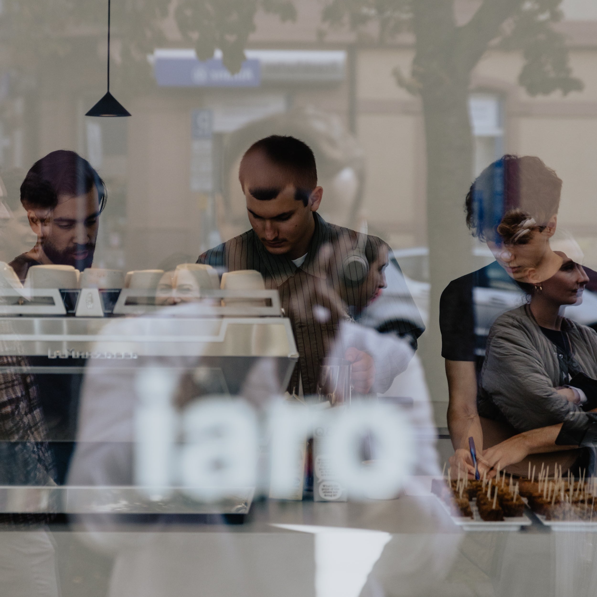 café window view of three baristas making coffee