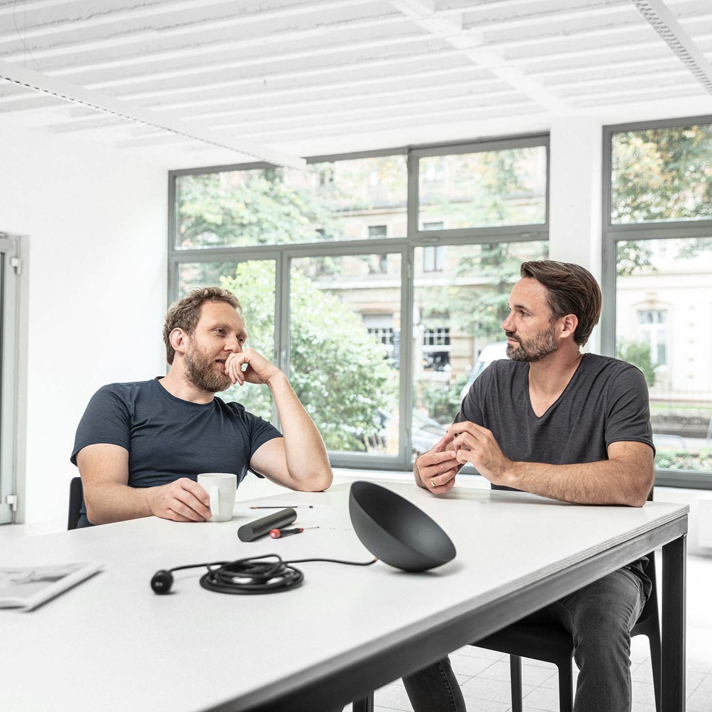 The head designers behind the Nyta Lighting brand sitting together at a table in their studio.