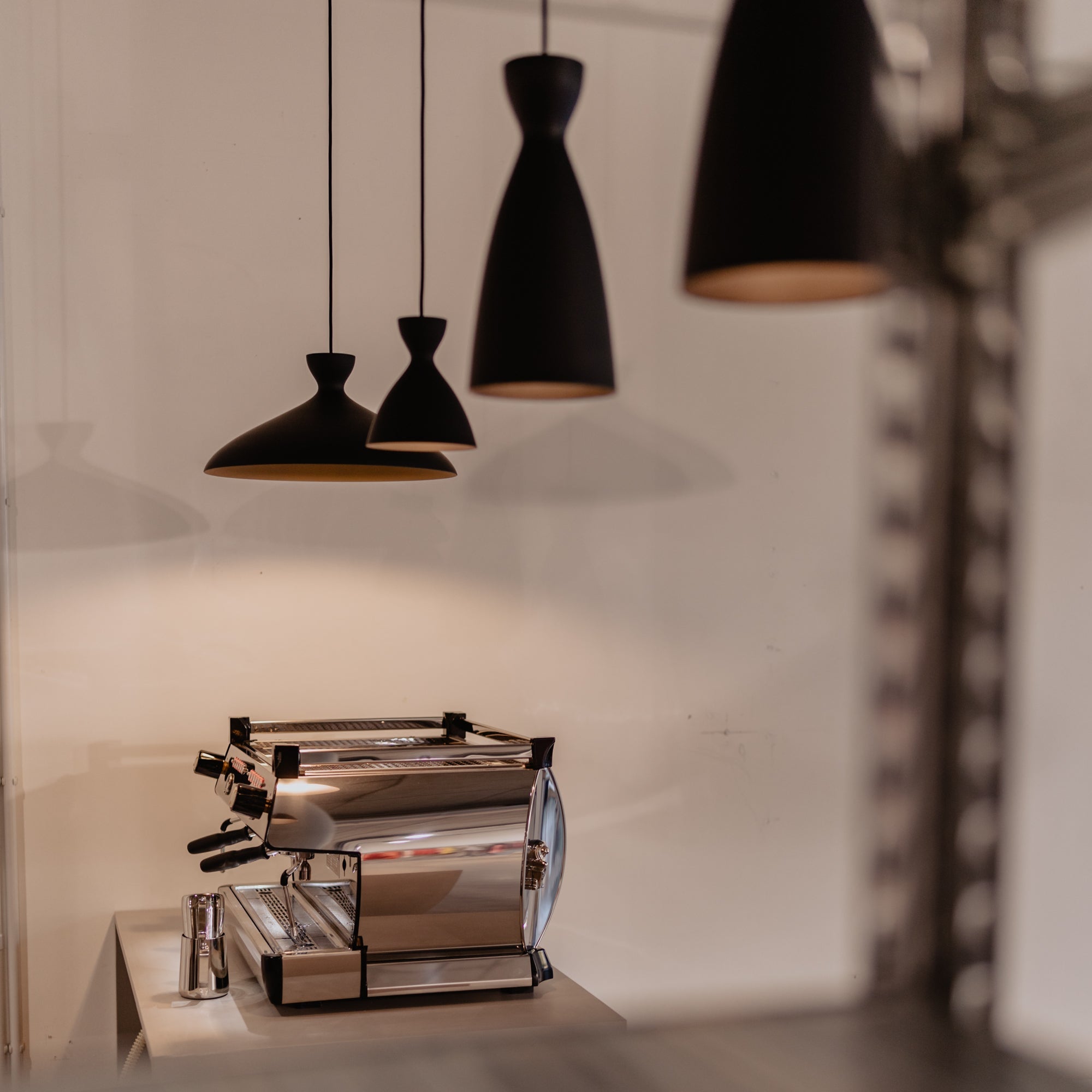 Four black pendant lights designed and manufactured by nyta are hanging over the bar at the iaro pop-up store.