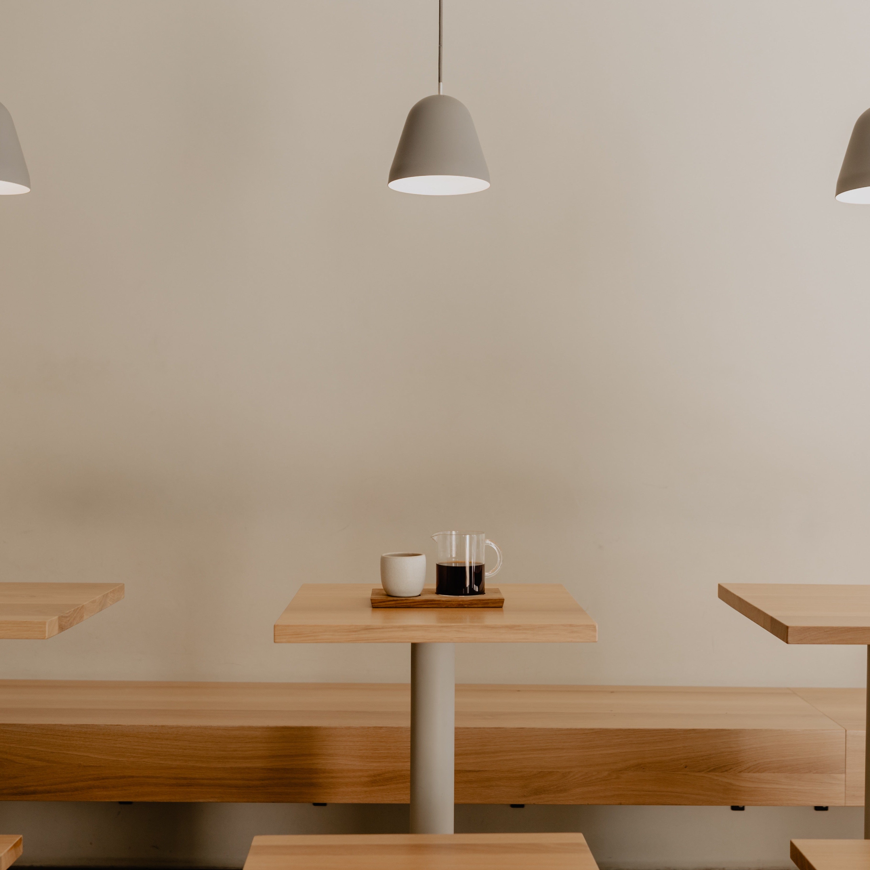 Tables in the iaro West coffeeshop with Nyta Tilt S design lamps hanging overtop.